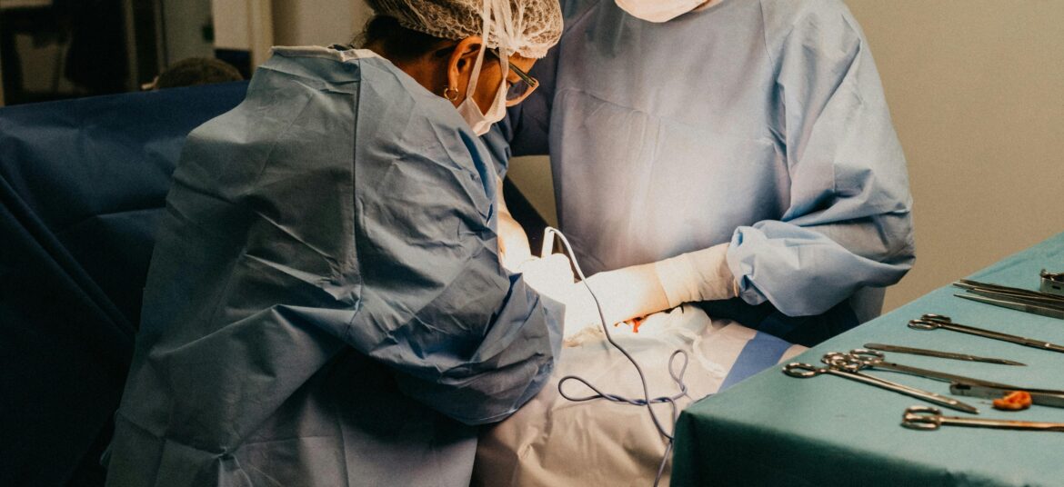 Two surgeons in an operating room conducting surgery under bright lights.